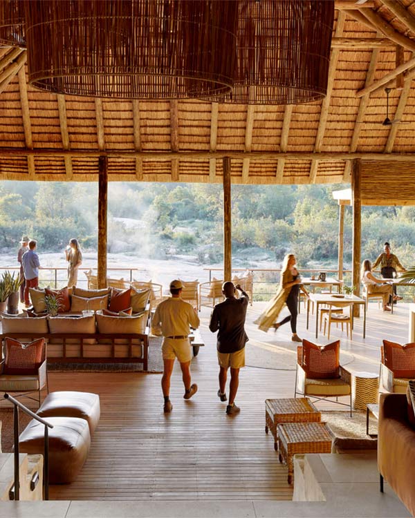 Sand River camp view with riverine forest canopy, open Land Rover at dusk.